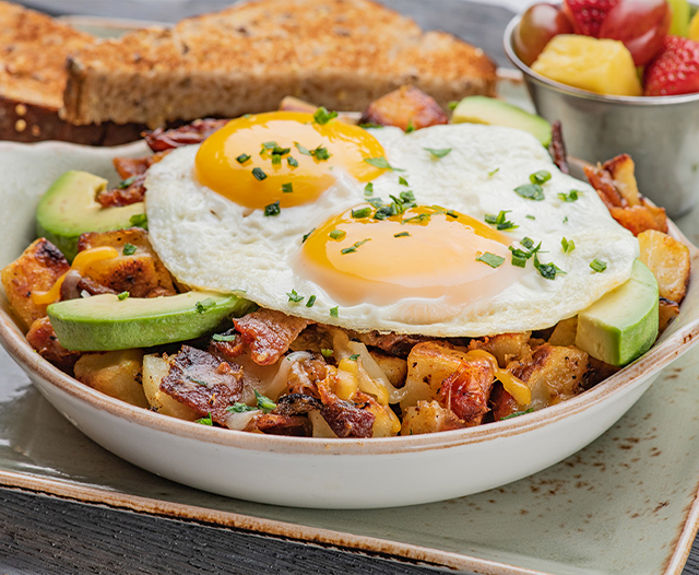A breakfast bowl with eggs, potatoes and avocado